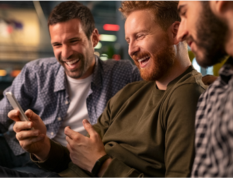 Man on phone looking at sports with friends smiling